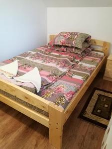 a wooden bed with a quilt on it in a room at Pensiunea ,,Suciu" in Răchiţele