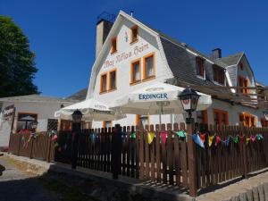 a fence in front of a white building with an umbrella at Pension und Restaurant Die Burg in Ehrenfriedersdorf