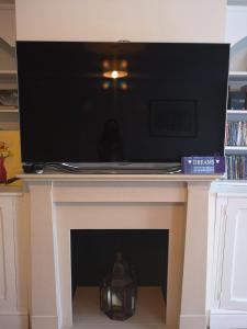 a flat screen tv sitting on top of a fireplace at Rooms close to Wimbledon tennis in London