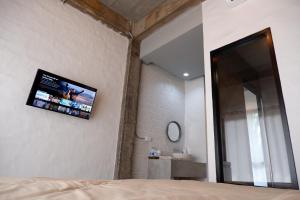 a bedroom with a flat screen tv on the wall at Black Elephant Boutique in Suratthani