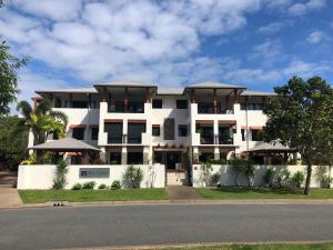 a white building on the side of a street at Luxury marina view Apartment cairns in Trinity Beach