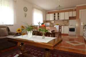 a kitchen and living room with a table with flowers on it at Apartman Matej in Otočac