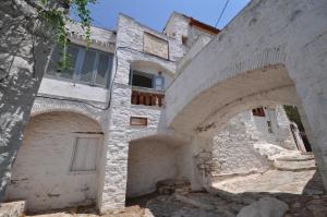 an old building with arches and a clock on it at Rallou House Hydra in Hydra