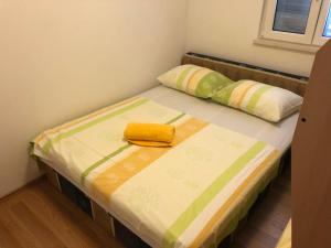 Apartments Volarevic في بلاتشي: سرير فيه منشفة صفراء تجلس فوقه