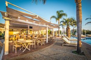 a patio with tables and chairs next to a pool at Parthenis Hotel & Suites in Malia