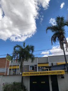 ein Hotel mit zwei Palmen vor einem Gebäude in der Unterkunft Hotel Pousada Marista in Goiânia
