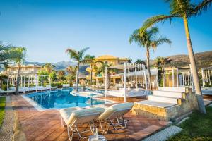 a resort swimming pool with chairs and palm trees at Parthenis Hotel & Suites in Malia