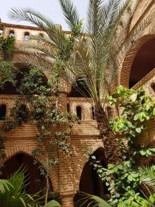 Hotel Salsabil في مراكش: نخلة أمام مبنى من الطوب