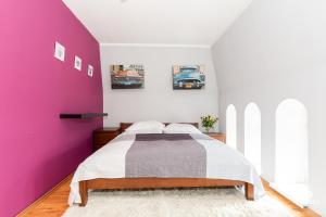 コウォブジェクにあるJantar Apartamenty - Loft u Aktoraの紫の壁のベッドルーム1室、ベッド1台が備わります。