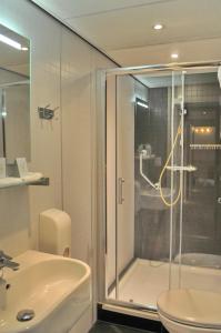 a bathroom with a shower and a toilet and a sink at Hotel Het Galjoen in Dronten