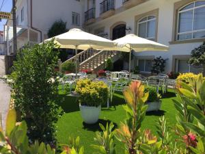 eine Terrasse mit Tischen, Stühlen und Sonnenschirmen in der Unterkunft Hotel Casa Portuguesa in Meaño