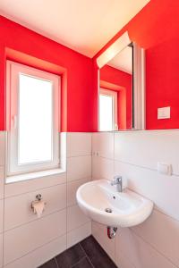 ゲーレンにあるVilla Mia Nr 1 mit Terrasse EG 1 Raum Wohnungの赤い壁のバスルーム(シンク、鏡付)