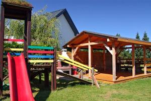 a wooden gazebo with a slide and a playground at Pokoje Goscinne ANNA in Ostrowo
