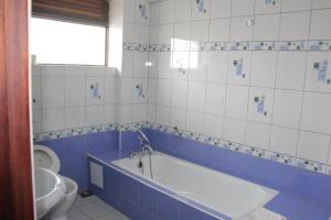a blue and white bathroom with a tub and a toilet at Hotel Jfrigh in Kampala