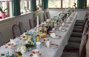 einen langen Tisch mit Geschirr und Flaschen darauf in der Unterkunft Pension "Parkhotel" Blankenhain in Blankenhain