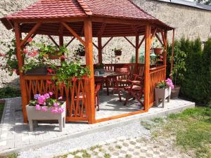 a wooden gazebo with a table and chairs and flowers at Ubytovanie na Spiši in Spišské Vlachy