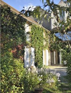 une maison couverte de lierre avec un jardin en face de celle-ci dans l'établissement Le Compostelle, à Vézelay