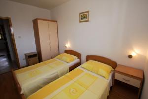 two beds in a small room with two tables at Apartments Elia in Mandre