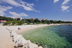 a beach with people sitting on the sand and the water at Apartments Elia in Mandre