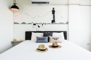 Un dormitorio con una cama con dos sombreros. en Dwell Phuket Airport Hotel at Naiyang en Nai Yang Beach