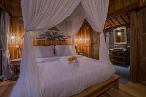 Un dormitorio con una cama con dosel y flores. en Ganesh Villa, en Ubud