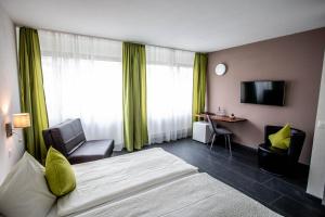 トゥーンにあるホテル アム シュロスのベッド、椅子、テレビが備わるホテルルームです。