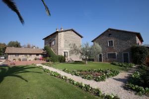 una antigua casa de piedra con un jardín delante de ella en I Casali della Parata en Velletri