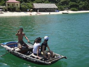 three people sitting in a boat on the water at Phuong Mai Family Hotel in Cat Ba