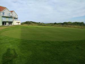 a green golf course with a house in the background at Location vue mer WIFI in Wimereux