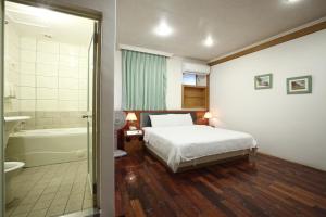 una camera da letto con un letto e un bagno con vasca di Long Shan Hotel a Jiaoxi