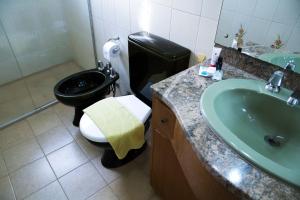 baño con aseo negro y lavamanos en Piano B&B + Coworking, en Porto Alegre