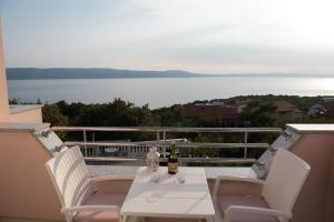 een tafel en stoelen op een balkon met uitzicht op het water bij Villa Mara Smokvica Krmpotska in Klenovica