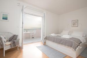 een witte slaapkamer met een bed en een balkon bij Villa Mara Smokvica Krmpotska in Klenovica