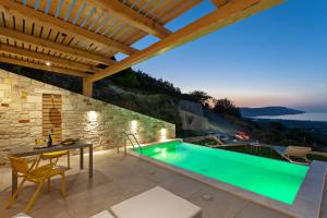 a villa with a swimming pool and a table and chairs at Thea Villas in Kournás