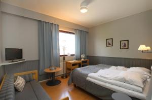 pokój hotelowy z łóżkiem i kanapą w obiekcie Hotelli Kainuu w mieście Kuhmo