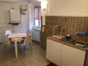 eine Küche und ein Esszimmer mit einem Tisch und einem Waschbecken in der Unterkunft Alba in Mele