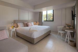 Un dormitorio con una gran cama blanca y una mesa en Quinta Elvira, en Cuernavaca