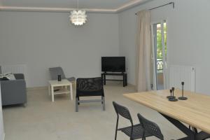 ein Wohnzimmer mit einem Tisch, Stühlen und einem TV in der Unterkunft Tilemachos House near Corfu town in Potamós