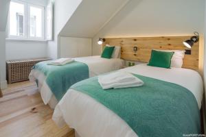 een slaapkamer met 2 bedden met groene en witte lakens bij Cardal Deluxe Apartment in Lissabon