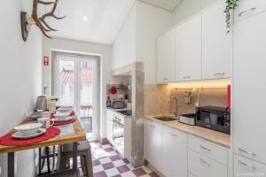 een keuken met witte kasten en een houten tafel bij Cardal Deluxe Apartment in Lissabon