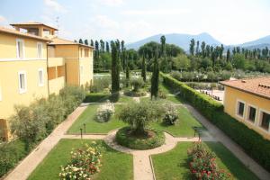 einen Garten mit einem Brunnen, Bäumen und Gebäuden in der Unterkunft Delfina Palace Hotel in Foligno