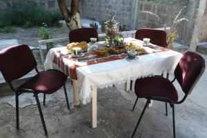 a table with a white table cloth on it with chairs at Guest House David's B&B in Gyumri
