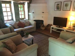 uma sala de estar com sofás e uma televisão de ecrã plano em Fig Garden Cottages em Kayakoy