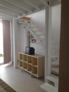 a staircase in a room with a tv and a shelf at CASA NA VILA HISTÓRICA DE MOURÃO in Mourão