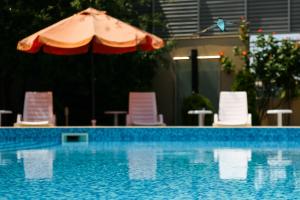 a swimming pool with an umbrella and chairs at Apart-Hotel Onegin & Thermal Zone in Sozopol