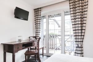 a bedroom with a desk and a bed and a window at Strandhotel Sille in Reifnitz