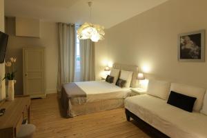 a bedroom with two beds and a couch and a chandelier at Le Cercle Chambres climatisées in Coligny
