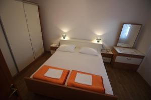 a bedroom with a white bed with two orange seats at Apartman Anka in Novi Vinodolski