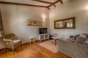 uma sala de estar com um sofá e uma televisão em Monte Da Galrixa na Zambujeira do Mar