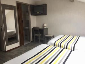 a hotel room with two beds and a mirror at Hôtel de L'Avenue in Tarbes